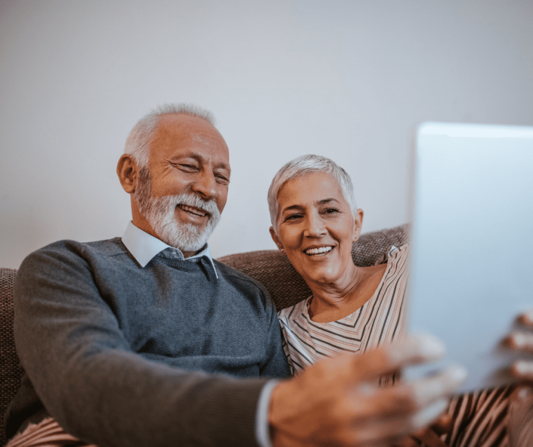 An elder couple dressed nicely and using an iPad to talk to someone