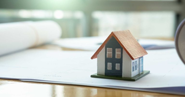 A toy house sitting on top of papers.