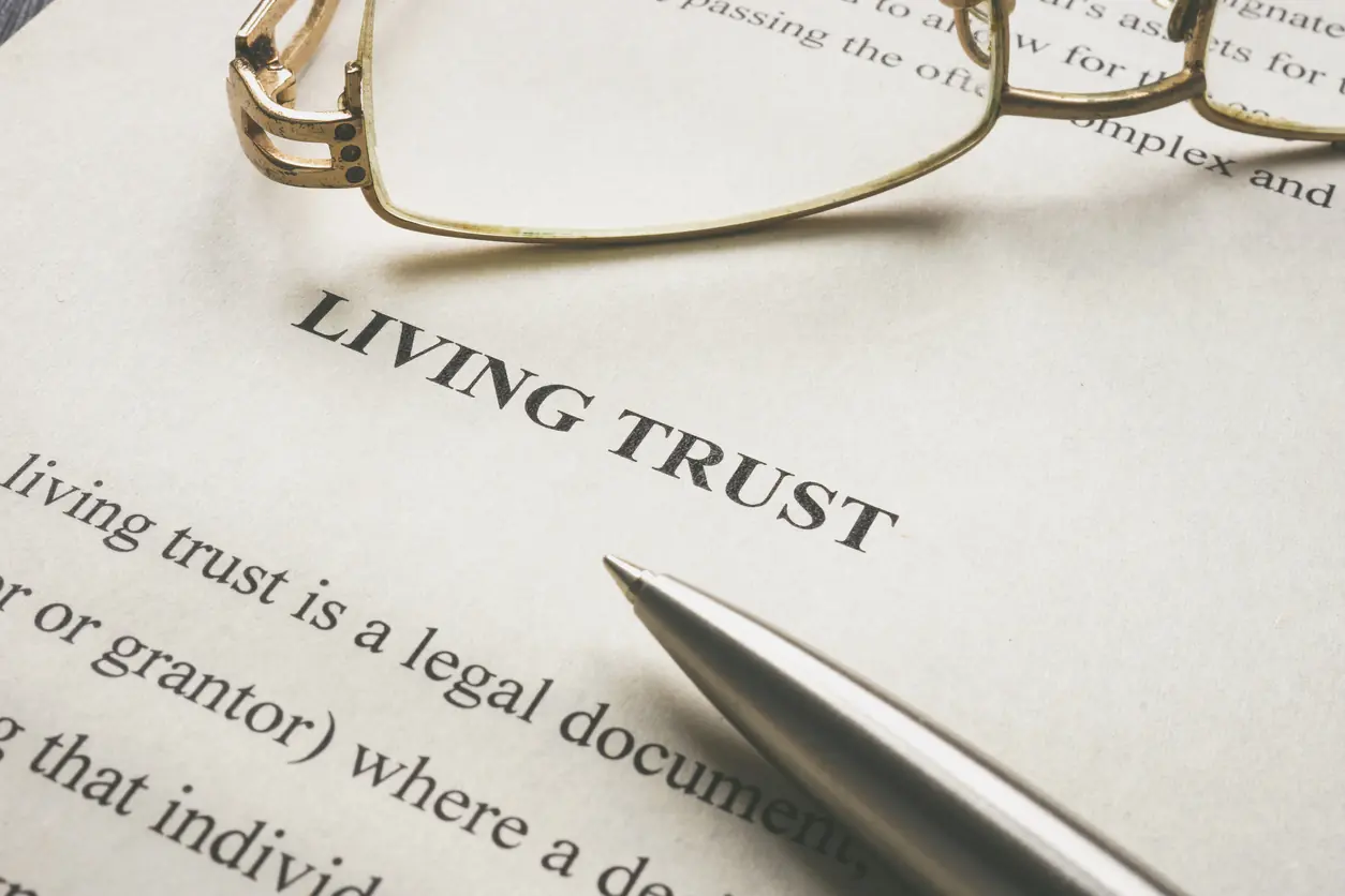 A pen and glasses on top of a living trust document.