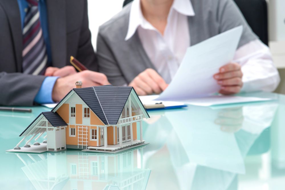 House model on table with agents reviewing documents